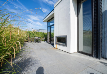 Buitenterras van Cube Exclusif 4 op Schoneveld in Nederland, met hoge grassen en eigentijds ontwerp.