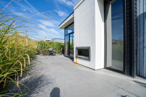 Buitenterras van Cube Exclusif 4 op Schoneveld in Nederland, met hoge grassen en eigentijds ontwerp.