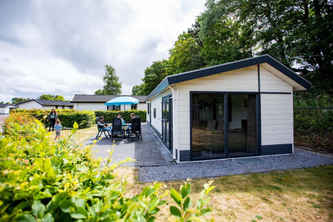 Gezin geniet van het terras bij Comfort cabin in EuroParcs Noordwijkse Duinen, Nederland.
