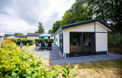 Familia disfruta del patio exterior en la cabaña Comfort en EuroParcs Noordwijkse Duinen, Países Bajos.