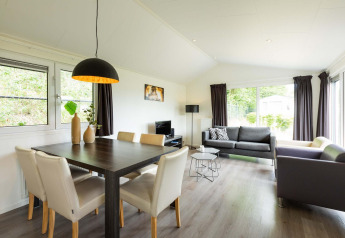Lys og moderne stue i en Comfort-hytte på EuroParcs Noordwijkse Duinen, Nederlandene, med store vinduer.