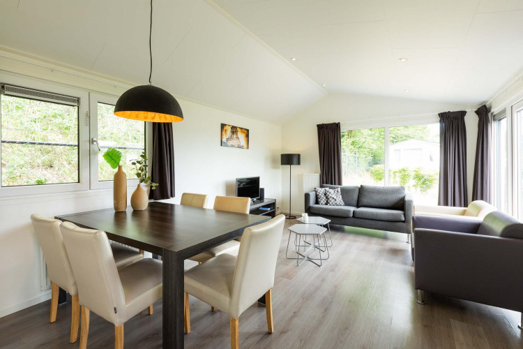 Helles, modernes Wohnzimmer in einer Comfort-Hütte im EuroParcs Noordwijkse Duinen, Niederlande, mit großen Fenstern.