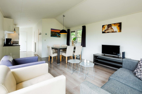 Moderne woonkamer in een Comfort cabin bij EuroParcs Noordwijkse Duinen met eetruimte en kitchenette.