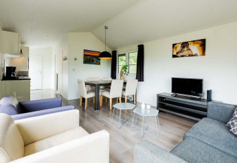 Moderne opholdsstue i en Comfort-hytte ved EuroParcs Noordwijkse Duinen med spiseplads og køkken.