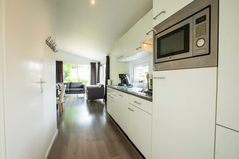 Heldere moderne keuken in een Comfort-hut bij EuroParcs Noordwijkse Duinen, Nederland, met zicht op de zitkamer.