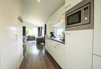 Lys og moderne køkken i en Comfort-hytte på EuroParcs Noordwijkse Duinen, Holland, med stue i baggrunden.