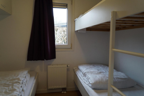 Soveværelse med køjesenge og vindue i hytten Comfort på EuroParcs Noordwijkse Duinen, Holland.