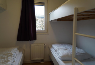 Soveværelse med køjesenge og vindue i hytten Comfort på EuroParcs Noordwijkse Duinen, Holland.