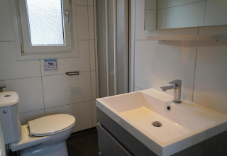 Moderne badkamer in de Comfort-blokhut bij EuroParcs Noordwijkse Duinen met toilet, wastafel en douche.