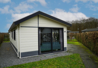 Udvendig billede af Comfort-hytte ved EuroParcs Noordwijkse Duinen i Holland med hæk og grussti.