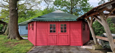 Foto de Writers hut, una pequeña casa roja de madera con techo verde en Zomerlicht, Países Bajos.