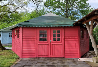 Foto de Writers hut, una pequeña casa roja de madera con techo verde en Zomerlicht, Países Bajos.