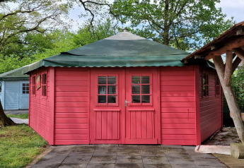 Et billede af Writers hut, et lille hus med røde trævægge og grønt tag ved Zomerlicht i Holland.