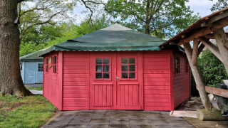 Foto der Writers Hut, einem kleinen roten Häuschen mit grünem Dach bei Zomerlicht in den Niederlanden.