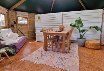 Intérieur chaleureux de la cabane de l’écrivain à Zomerlicht, Pays-Bas, avec meubles en bois et plantes.
