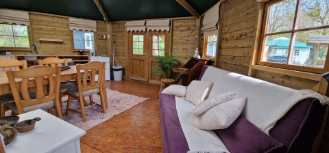 Innenansicht der Writers hut in Zomerlicht, Niederlande, mit Holzdekor, Sofa, Esstisch und großen Fenstern.