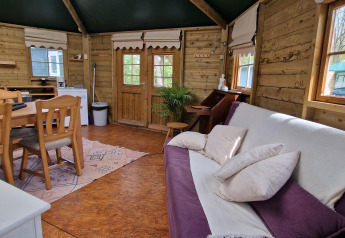 Vue intérieure de la Writers hut à Zomerlicht, Pays-Bas, avec des murs en bois, un canapé et une table à manger.