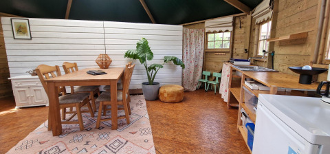Vista interior de la Writer's Hut en Zomerlicht, Países Bajos, con mesa de comedor, cocina y decoración.