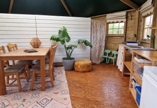 Vista interior de la Writer's Hut en Zomerlicht, Países Bajos, con mesa de comedor, cocina y decoración.