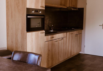 Moderne Küchenzeile in der Chalet Lodge im Ferienpark Eigen Wijze, Niederlande, mit Holzoptik.