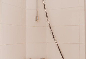 Moderne douche met handdouche en mengkraan, gemonteerd op lichte tegels in een lodgebadkamer.