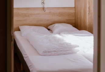 Smal slaapvertrek in een lodge met twee enkele bedden naast elkaar, witte lakens en houten kasten.