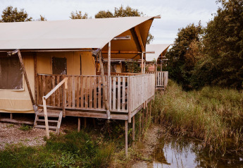Tente glamping confortable au parc de vacances Eigen Wijze aux Pays-Bas, sur pilotis au bord de l'eau.