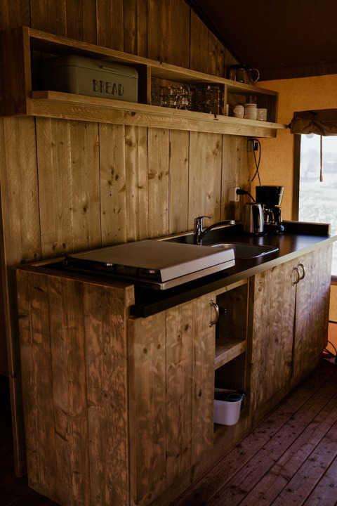 Zona de cocina rústica de madera en una tienda glamping cómoda en Holiday park Eigen Wijze, Países Bajos.