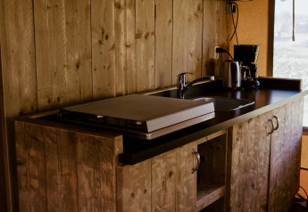 Zona de cocina rústica de madera en una tienda glamping cómoda en Holiday park Eigen Wijze, Países Bajos.