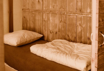 Lit douillet avec murs en bois dans une tente glamping confortable au Holiday park Eigen Wijze, Pays-Bas.