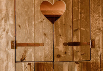 Puerta de madera con recorte en forma de corazón en tienda glamping en Holiday park Eigen Wijze, Países Bajos.