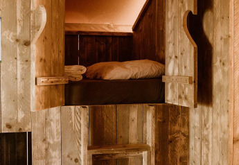 Letto in legno con scala in una confortevole tenda glamping al Holiday park Eigen Wijze, Paesi Bassi.