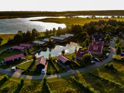 Vista aerea di una comoda tenda glamping al Holiday park Eigen Wijze, Paesi Bassi, vicino a un lago al tramonto.