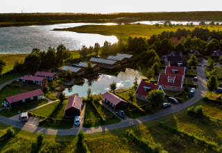 Vista aerea di una comoda tenda glamping al Holiday park Eigen Wijze, Paesi Bassi, vicino a un lago al tramonto.