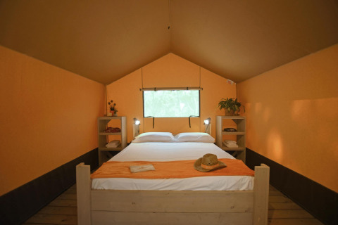 Vista interior de la tienda Safari tent Cozy con cama doble en TinyParks Cast Away, Países Bajos, con desayuno.
