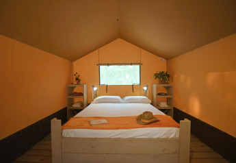 Vista interna della tenda Safari tent Cozy con letto matrimoniale presso TinyParks Cast Away nei Paesi Bassi, colazione inclusa.