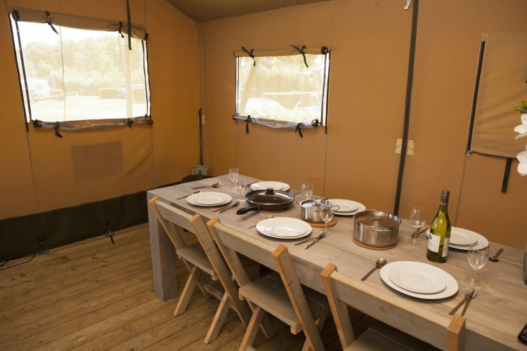 Interior de una tienda safari de lujo con mesa puesta en Holiday park De Boshoek, Países Bajos.