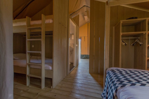 Innenansicht eines Luxus-Safari-Zeltes mit Holzboden und Etagenbetten im Ferienpark De Boshoek, Niederlande.