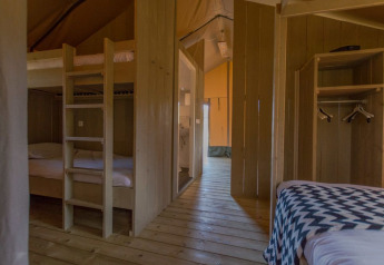 Interieur van luxe safaritent met houten vloer en stapelbedden bij Holiday park De Boshoek, Nederland.