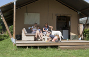 Familia con perro relajándose frente a tienda safari de lujo en Holiday park De Boshoek, Países Bajos.