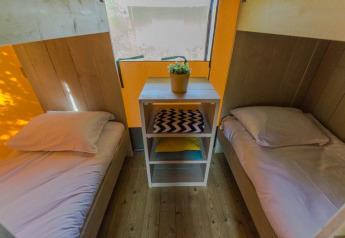 Two single beds and a table with a plant in a luxury safari tent at Holiday park De Boshoek, Netherlands.