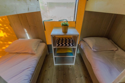 Deux lits simples et une table avec une plante dans une tente safari de luxe à Holiday park De Boshoek, Pays-Bas.