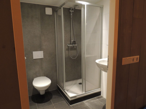 Bagno moderno in una tenda safari di lusso con doccia, WC e lavandino all’Holiday park De Boshoek, Paesi Bassi.