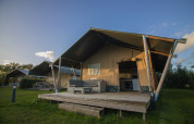 Tienda safari en Holiday park De Boshoek, Países Bajos, con terraza de madera y asientos en el exterior.