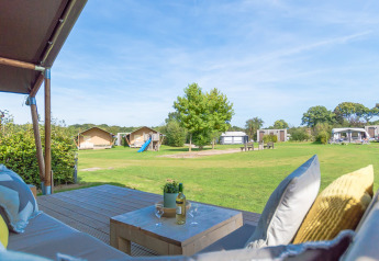 Vue depuis la terrasse d'une tente safari au Holiday park De Boshoek aux Pays-Bas, pelouse et aire de jeux.