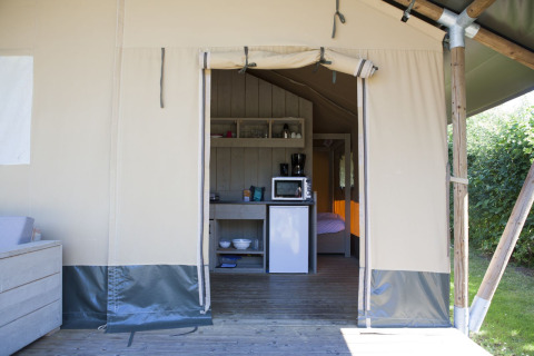 Innenraum eines Safari-Zeltes im Holiday Park De Boshoek, Niederlande, mit Küchenzeile und Bett.