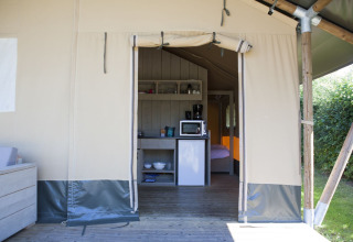 Innenraum eines Safari-Zeltes im Holiday Park De Boshoek, Niederlande, mit Küchenzeile und Bett.