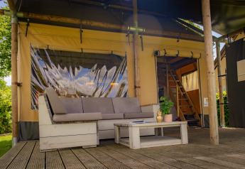 Buiten zithoek van een luxe Safarilodge tent bij Vakantiepark De Boshoek in Nederland met bank en tafel.