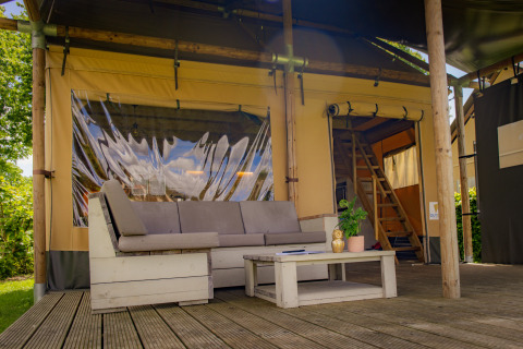 Buiten zithoek van een luxe Safarilodge tent bij Vakantiepark De Boshoek in Nederland met bank en tafel.