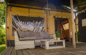 Buiten zithoek van een luxe Safarilodge tent bij Vakantiepark De Boshoek in Nederland met bank en tafel.